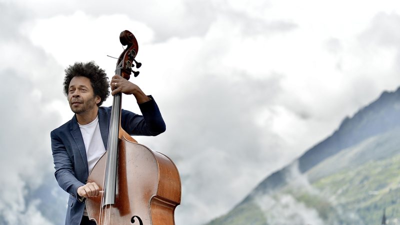 Kham Meslien playing upright bass in the Alps